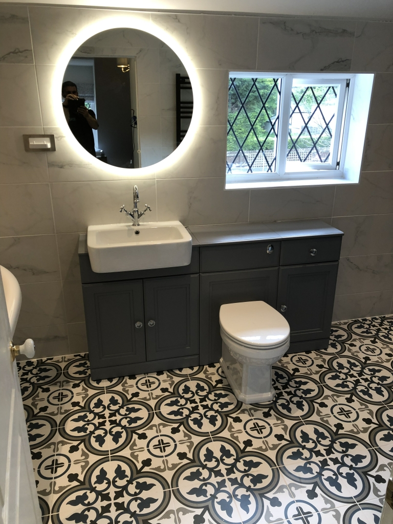 Grey vanity with backlit mirror and patterned floor tiles